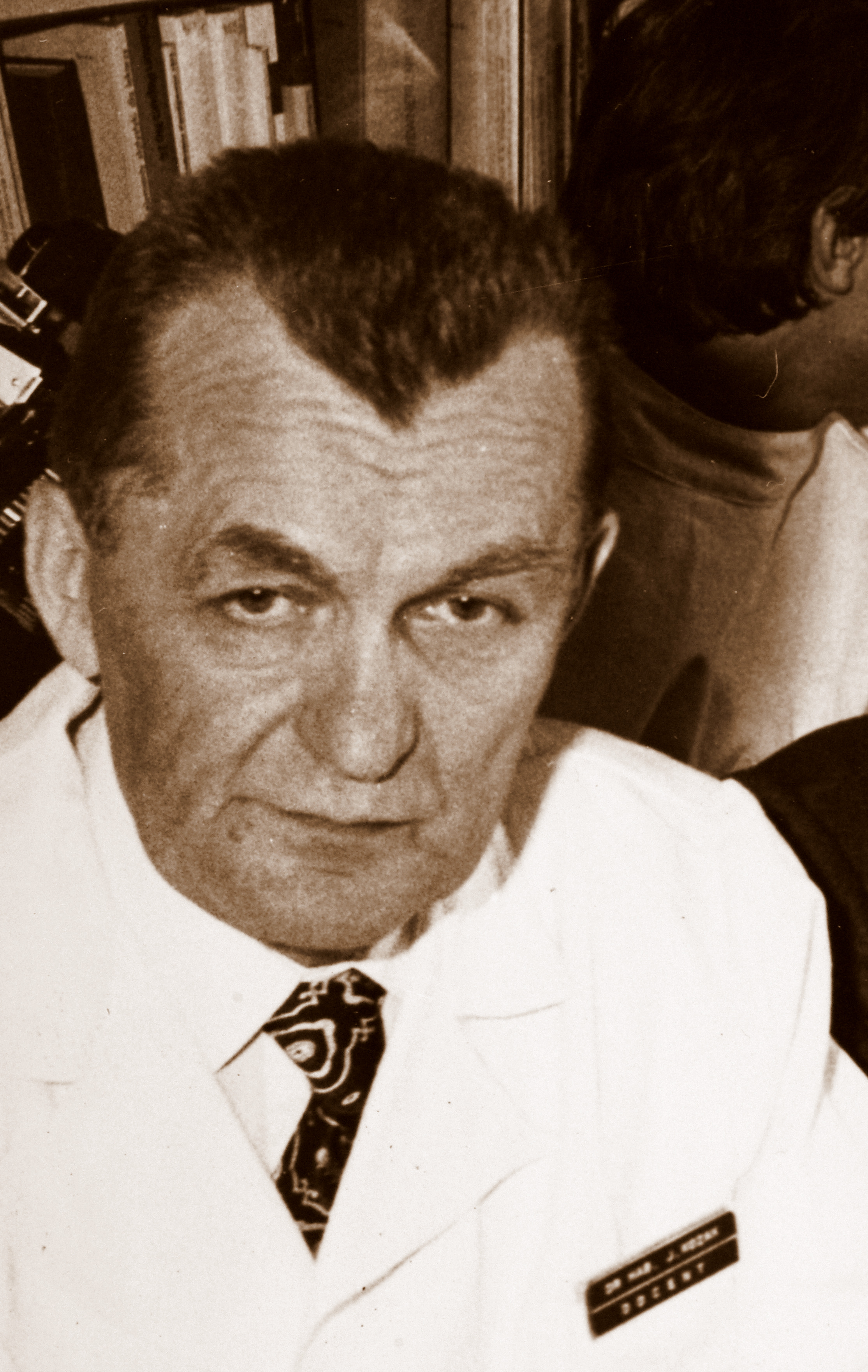 Dojrzały mężczyzna w kitlu patrzący w obiektyw. Zdjęcie czarno-białe